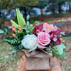 Pink and white roses with purple orchids in a burlap-wrapped box