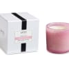 Pink scented candle in a glass holder beside its white box