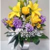 Yellow lilies and purple flowers in a silver vase