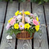 Basket of yellow, pink, and lavender flowers on a wooden deck