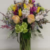 Mixed bouquet of roses, tulips, and purple orchids in a glass vase