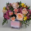 Bouquet of peach roses and pink flowers in a square glass vase