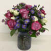 Pink and white roses with purple daisies in a glass vase