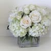 White roses and hydrangeas arranged in a clear square vase