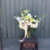 White and pale green floral arrangement in a glass vase with a ribbon