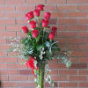 Tall vase arrangement of red roses with trailing greenery