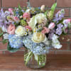 Pastel bouquet of roses, tulips, hydrangeas, and lilies in a glass vase