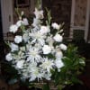 Large white floral arrangement in a basket with a small angel figurine