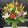 Mixed bouquet of lilies, gerbera daisies, and roses in a glass vase