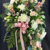 Standing floral spray with white and peach flowers and a pink ribbon