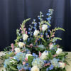 Large floral arrangement with white roses, blue blooms, and pink accents