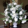 White floral arrangement in a white vase with spiky blooms and carnations