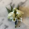 White rose boutonniere with small white accent flowers and fern fronds