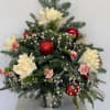 Christmas arrangement with white flowers, red ornaments, and evergreen branches in a glass vase