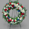 Circular floral wreath on a stand with red, white, and blue flowers