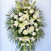 White floral standing spray with lilies and roses on a palm backdrop