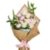 Bouquet of pale pink and white roses wrapped in brown paper with a pink ribbon
