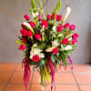 Tall bouquet of red roses, white calla lilies, and lilies in a glass vase