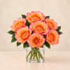 Orange and pink roses arranged in a clear glass vase
