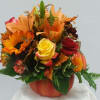 Autumn bouquet in a pumpkin-shaped vase with sunflowers, roses, and lilies