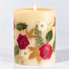 Floral-decorated pillar candle with a lit flame