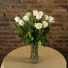 White roses in a clear glass vase on a table