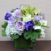 Lavender and white floral arrangement in a square glass vase