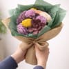 Handheld bouquet of multicolored flowers wrapped in burlap and green paper