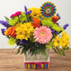 Colorful birthday flower arrangement in a decorated square container