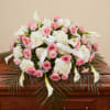 Pink roses and white calla lilies arranged with hydrangeas and a white ribbon