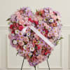 Heart-shaped floral wreath with pink and purple flowers and a satin ribbon