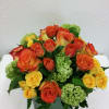 Bouquet of orange and yellow roses with green hydrangeas in a square glass vase
