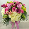 Pink and white mixed bouquet in a clear glass vase with a pink ribbon