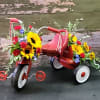 Flower-covered red tricycle with sunflowers and mixed blooms