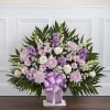 Lavender and white floral arrangement with a purple ribbon in a white vase