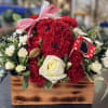 Red carnations and white roses in a wooden box with a ribbon and Georgia flag pick.