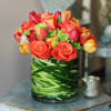 Orange roses and tulips arranged in a glass vase.