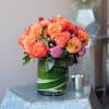 Orange roses and dahlias in a green glass vase