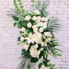 White floral standing spray with roses, lilies, and greenery
