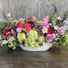 Low floral centerpiece with pink and purple roses in a white bowl vase