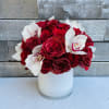 Red roses and white orchids arranged in a white vase