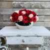 Red and blush roses arranged in a silver bowl on a white table