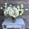 White floral arrangement in a clear glass vase on a small table