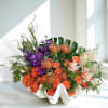 Orange and purple floral arrangement in a white shell-shaped vase