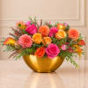 Bright mixed bouquet in a gold bowl vase with pink, orange, and yellow blooms