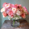 Pink and peach roses with white blooms in a clear glass vase
