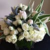 White roses and hydrangeas in a square glass vase with variegated leaves
