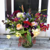 Colorful mixed flower arrangement with roses, dahlias, and tulips in a clear glass vase