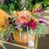 Autumn floral arrangement in a pumpkin container with peach and magenta blooms