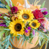 Sunflower arrangement in a pumpkin-shaped container with colorful mixed blooms